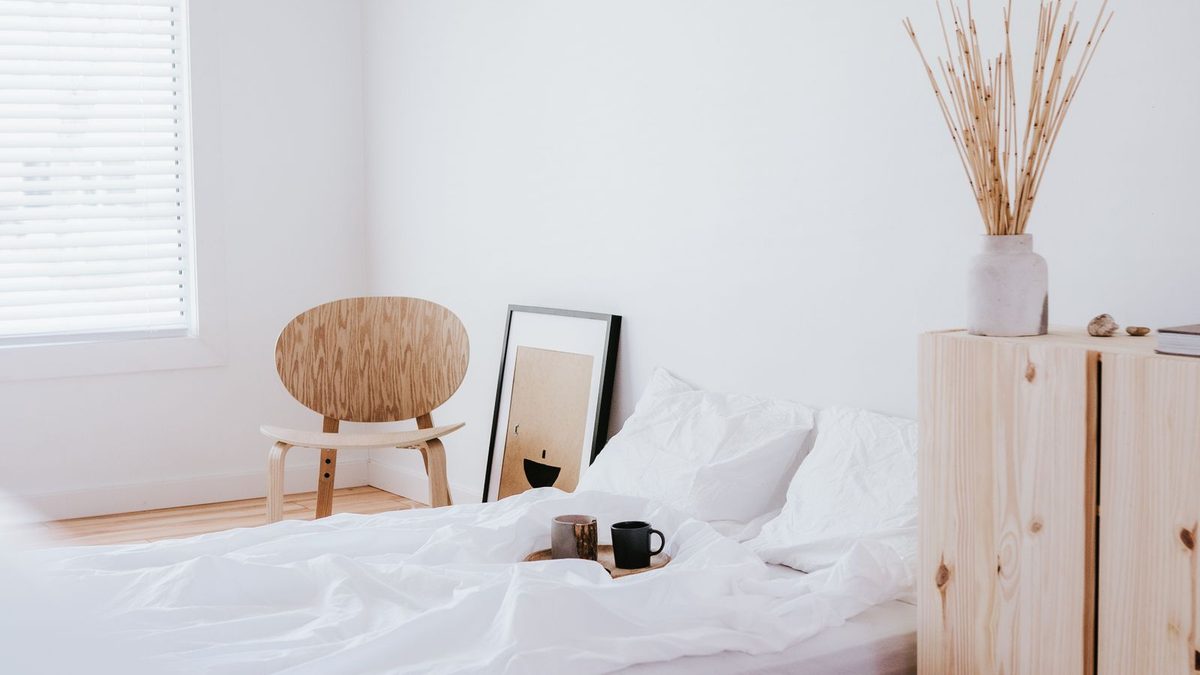A pine bed and a pine cabinet in a small white room with a wooden floor